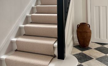 A neutral beige loop pile stair runner with a black and white checkered floor